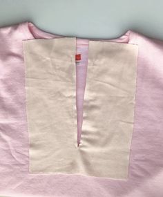 a pink and white shirt with a red patch on the chest, cut in half