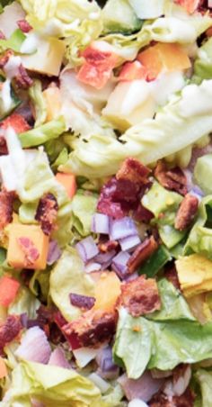 a salad with lettuce, tomatoes and bacon on it is shown in close up