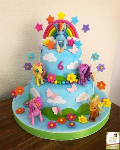 a birthday cake decorated with rainbows and ponies