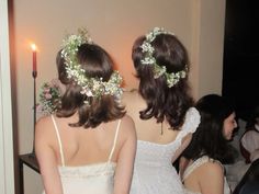 two women in white dresses standing next to each other with flower crowns on their heads