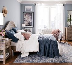 a bedroom with blue walls and white bedding in the center, along with a rug on the floor