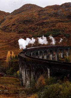 a train traveling over a bridge in the mountains