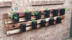 a wall mounted planter with several plants in it and hanging on the side of a brick building