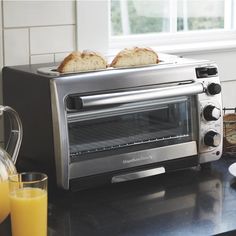 toaster oven with two slices of bread on top and orange juice next to it