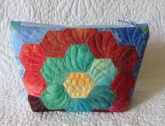 a multicolored zipper bag on a white bed