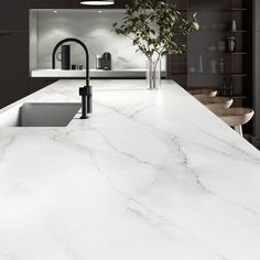 a white marble counter top with black faucet, sink and potted plant