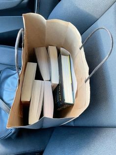 a bag filled with books sitting on top of a blue seat in the back of a car