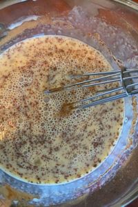 a mixing bowl filled with liquid and whisks