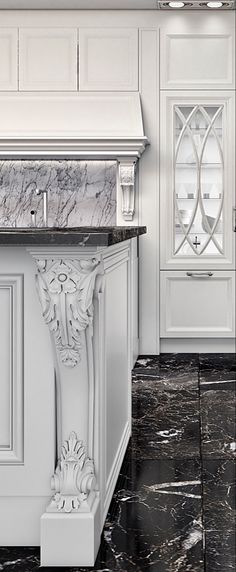 a white kitchen with marble counter tops and an ornate design on the cabinetry, along with black tile flooring