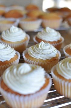 cupcakes with white frosting on a cooling rack