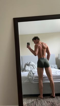 a shirtless man taking a selfie in front of a mirror with his cell phone