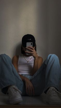 a woman sitting on the floor with her phone up to her face