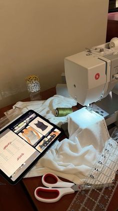 a sewing machine sitting on top of a wooden table next to scissors and other items