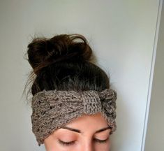 a woman wearing a knitted headband with her hair in a bun and looking down