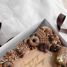 a birthday cake with chocolate frosting and decorations in a box on top of a table