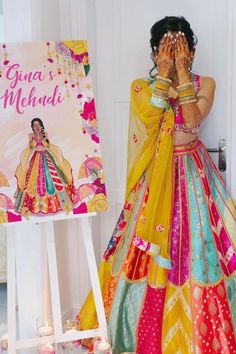 a woman in a yellow and red dress is holding her hands to her face while standing next to a book