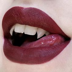 a woman's lips with white teeth and dark red lip glosses on them