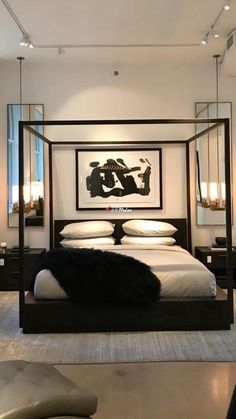 a bedroom with a four poster bed and white sheets, black furniture and artwork on the wall