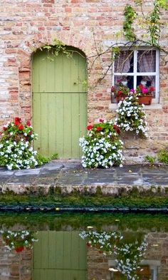 flowers are growing on the windowsills and in front of an old brick building