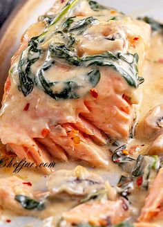 a piece of meat with spinach and cheese on it in a white sauce covered dish