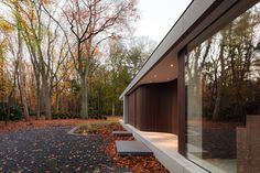 an exterior view of a house in the woods with trees and leaves on the ground