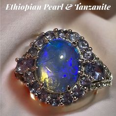 My New Favorite Gem! The Colors Are Astounding And You Wont Be Able To Stop Looking At Oval Shaped White Ethiopian Opal (10.88mm !) With 0.50ctw Tanzanite And 1.00ctw White Zircon Rhodium Over Sterling Silver Ring. Tanzanite Gemstones! It’s One The Rarest Gems List And They’ll Be Gone In 10 Yrs! Get Your Tanzanite Now! Even .5 Ctw Is Extremely Expensive! Info To Know: Measures Approximately 0.81"L X 0.64"W Metal Weight 2.25 G Band Width 0.08 G Primary Stone Opal Gemstone Gemopedia While We Often Dazzling Multi-stone Sapphire Jewelry, Tanzanite Gemstone With Center Stone As Gift, Opal Jewelry With Center Stone In White Gold, White Gold Opal Jewelry With Center Stone, Tanzanite Gemstones Perfect For Gifts, Tanzanite Multi-stone Round Cut Rings, Tanzanite Multi-stone Rings With Round Cut, Dazzling Tanzanite Jewelry With Prong Setting, Oval Tanzanite Jewelry With Gemstone Accents