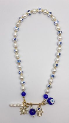 18 inch, hand-Painted Blue Evil Eye Glass Pearl Necklace with 5 charms (blown glass Greek evil eye, blue glass bead & moonstone crystal, cz-crusted hamsa, gold starburst), with gold vermeil clasp. White Evil Eye Beaded Necklace, Evil Eye Jewelry Aesthetic, Hand Painted Blue Spiritual Necklace, Capri Aesthetic, Evil Eye Blue, Gold Starburst, Greek Evil Eye, Moonstone Crystal, Eye Glass