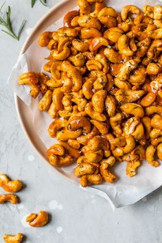 roasted cashews on a plate with rosemary sprigs