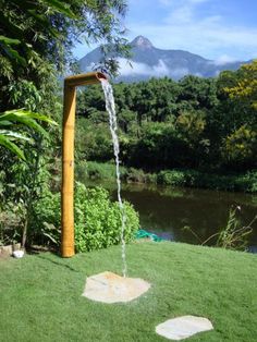 a water fountain in the middle of a lush green field