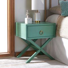 a nightstand with a lamp on top of it next to a bed