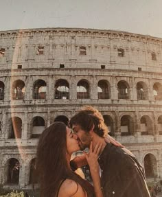 a man and woman kissing in front of the colossion, with sunlight streaming through them