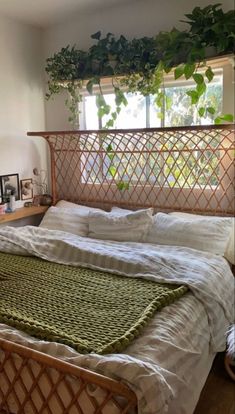 the bed is made with white linens and green plants hanging from the headboard