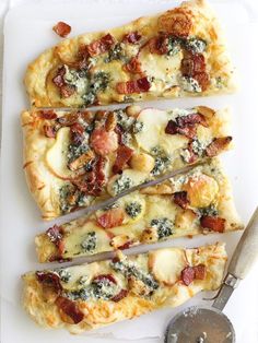 four slices of pizza sitting on top of a white plate next to a knife and fork