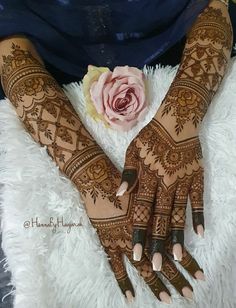 two hands with henna tattoos and a flower