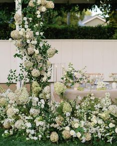 white flowers and greenery are arranged around a table