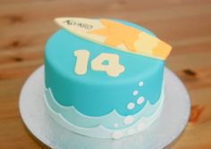 a blue cake with a surfboard on top and the number fourteen written in white