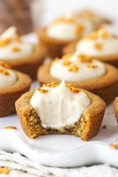 several cookies with white frosting and orange zest sprinkles on top