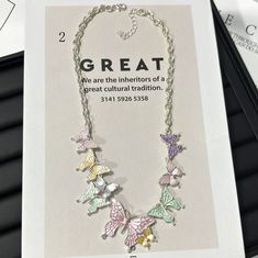 a necklace with butterflies on it sitting in front of a card that says great we are the interiors of a great cultural tradition