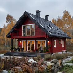 a red house with a black roof and windows on the front porch is surrounded by rocks