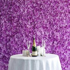 a wine bottle and two glasses sitting on a table with purple flowers in the background