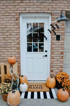 pumpkins and gourds on the front steps of a house with a welcome mat