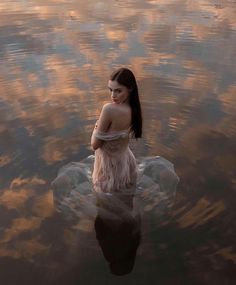 a woman is sitting in the water with her hands on her hips and looking off into the distance