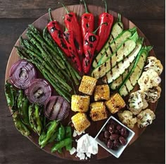 a platter with grilled vegetables and dipping sauces on it, including asparagus