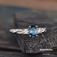 a blue and white diamond ring sitting on top of a rock