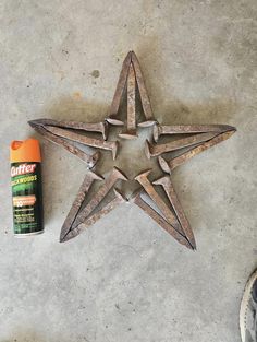 a rusty metal star next to a can of spray paint on the ground with someone's feet standing near it