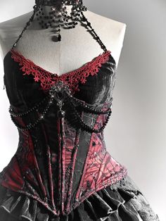 Stunning Victorian Goth Corset: This exquisite piece features a handmade black bead chain neckline adorned with a removable brooch. The corset is reinforced with four metal bones for a perfect fit and is crafted from a red, shiny fabric overlaid with intricate spiderweb lace. Embrace your inner royalty with its regal vampire vibes.   	 		 			Size 			S 			M 			L 		 		 			Waist 			64 			68 			72 		 		 			Full Length 			31 			32 			33 		 		 			Upper Circumference 			88 			92 			96 		 		 			Hem Circ Dnd Clothes, Spiderweb Lace, Velvet Corset Top, Modern Mythology, Red Vampire, Red And Black Corset, Gothic Spider, Goth Fits, Vampire Fashion