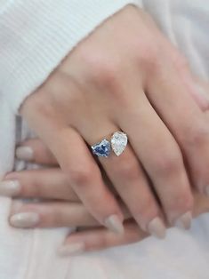 a close up of a person's hand wearing a ring with two diamonds on it