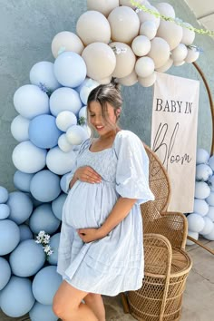 a pregnant woman standing in front of balloons