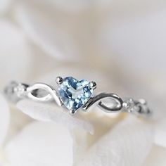 a heart shaped aqua blue topazte ring with white gold accents on a flower