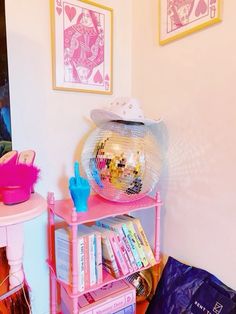 there is a disco ball on top of a pink shelf in the corner of this room